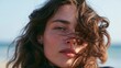 © Lifestyle Images - Close-up portrait of a young woman's face. she has shoulder-length, wavy hair that is blowing in the wind. her eyes are closed and her expression is peaceful and serene.