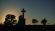 © Austockphoto - Silhouette of a weeping angel statue and cross at sunrise in a cemetery