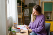 © Westend61 - Woman studying and writing in notebook at home with natural light