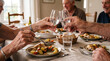© Arra Vais - Senior hands dinner, with elder hands serving roasted chicken and vegetables at family table. Senior hands dinner features others toasting glasses, creating warm atmosphere, celebrating friendship.