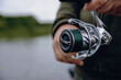 © smiltena - A spinning rod with a spinning reel in the hands of a fisherman
