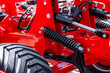 © NastyaPhoto - Agricultural machinery hydraulic cylinder and chassis tension spring. Modern farm machine pressure system component on metal frame with transport vehicle low pressure tire close up details.