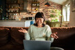 © Davor - Smiling woman having video call on laptop at home
