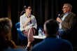 © DragonImages - Medium shot of Caucasian businesswoman and senior man speaking on stage during panel discussion, sharing expertise and leadership insights. Ideal for conference marketing and corporate communication