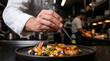 © Luiz - Chef's Artistry on a Plate: A skilled chef meticulously garnishes a gourmet dish of scallops and shrimp, showcasing culinary expertise in a bustling kitchen environment.