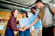 © we.bond.creations - Diverse business team stacking hands in a huddle, celebrating unity, collaboration, and shared success with happy expressions in an office