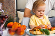 © Natalia Shmatova - Toddler examining a ripe apricot while sitting with father beside fresh fruit and tomato bruschetta outdoors