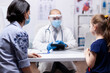 © DC Studio - Pediatrician wearing a face mask uses a tablet while consulting a child, showing pediatric healthcare and digital medical support.