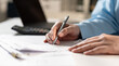 © Father_Studio - Close up of businesswoman hand writing on tax form at office desk. Accountant auditing financial invoice receipt, calculating budget or corporate management concept.
