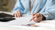 © Father_Studio - Businesswoman reviewing financial documents, tax paperwork, file folders, and business records on a laptop, representing accounting, document management, compliance, and office administration.