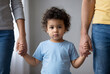 © Meow Creations - Cute curly haired toddler standing and holding hands with two adults standing on either side
