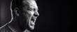 © itlada - Angry man screaming in profile view, captured in a dramatic black and white portrait with intense facial expression and dark background, ideal for mental health and stress concepts