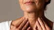 © 69 - Close-up of mature woman touching neck showing skincare or health concern with soft natural lighting and neutral background