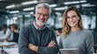 © CinimaticWorks - happy business colleagues laughing and smiling while using digital tablets in a modern workplace representing corporate teamwork success