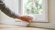 © SimpleDesignStudio - Person cleaning white window sill with cloth for home maintenance and spring cleaning chores
