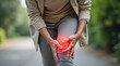 © Leonardo - Mujer mayor caminando lentamente mientras se sujeta la rodilla dolorida, con expresión preocupada e indicador médico de color rojo