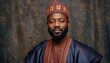 © 247 Stocks - Portrait of a distinguished man wearing traditional patterned attire and a matching cap against a textured dark backdrop in a studio setting