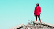 © Mirivox - Woman in red blazer stands on rubble against clear sky, symbolizing resilience and power after destruction, conceptual fashion shot