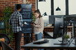 © DC Studio - Developer presents code errors with tablet as engineers use a tablet and wall display to review bugs, cloud computing and team software development in an IT office.