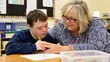 © firdol - Inclusive Education: Supportive Teacher Helping a Boy with Down Syndrome in Classroom