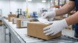 © Shakib - Logistics worker in white gloves applying label to cardboard box package.