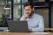 © Karla - Focused businessman working on laptop in modern office while thinking about a project