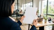 © MstMoyna - Business woman holding a blank white paper document in a modern bright office space for creative design mockup
