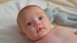© Krakenimages.com - Baby newborn bare chest gazing upward with drool on lip and knitted toy nearby in studio; calm curiosity.