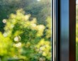 © Vaughn - close up detail of a modern triple glazed window with a slim dark aluminium frame and airtight seals against a softly blurred green garden for energy efficient passive house construction