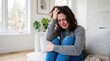© Karan - Sad woman sitting on a couch crying and holding her head in distress with distress depression emotional struggle