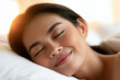 © Kowit - A woman peacefully sleeping with a relaxed expression on a white pillow, bathed in warm morning light.