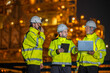 © BESTIMAGE - engineers team discussing petroleum engineering in oil refinery project collaboration at fuel industrial plant Group of petrol engineer using radio and laptop to work at site during nighttime