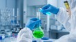 © Kohinur - Professional scientist pouring chemical liquid in laboratory, researcher in hazmat suit conducting clinical experiment, medical lab glassware with green and blue fluids