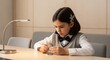 © mdthasinhasan - Little girl studying at desk. Focused schoolgirl doing homework in a bright classroom.