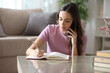 © PheelingsMedia - Serious woman talking on phone scheduling in agenda