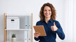 © Kaluya Stock - Smiling businesswoman holding digital tablet and showing thumbs up gesture in modern office