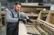 © Serhii - Carpenter working on sofa frame in furniture factory