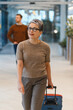 © Serhii - Mature woman traveling pulling luggage at airport