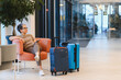© Serhii - Woman waiting with luggage in modern hotel lobby