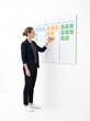 © gabriel - Woman writing on a Kanban board with sticky notes for project management