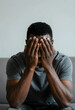 © Pixel-Shot - African american man covering his face with hands, expressing sadness, stress, and mental health issues