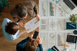 © Konstantin Yuganov - Team Analyzing Financial Data and AI Charts in Modern Office, Top View