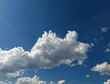 © Kenan Sonmez  - Fluffy white cumulus clouds floating in a vibrant deep blue summer sky.