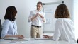 © volha_r - Business professional presenting financial data and market analysis on a flipchart during a corporate meeting, collaborating with female colleagues during a brainstorming session