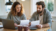 © MagicsPhotos - Couple reviewing household finances and monthly expenses at home