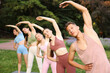 © New Africa - Group of people practicing yoga in park, selective focus