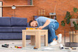 © Pixel-Shot - Young man with level assembling wooden table at home