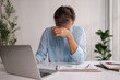 © David - Businessman clutching his head, looking exhausted, sits at a white office desk with a laptop and financial documents