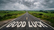 © Samirkhattak - Straight asphalt road with good luck written large in white letters across the surface with long straight country road phrase inspiration countryside