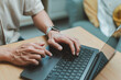 © winnievinzence - Close-up of a man hands typing on a laptop computer keyboard on desk while working from home, searching data, remote work and browsing online
